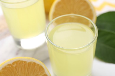 Photo of Shot glasses with tasty limoncello liqueur on table, closeup. Space for text