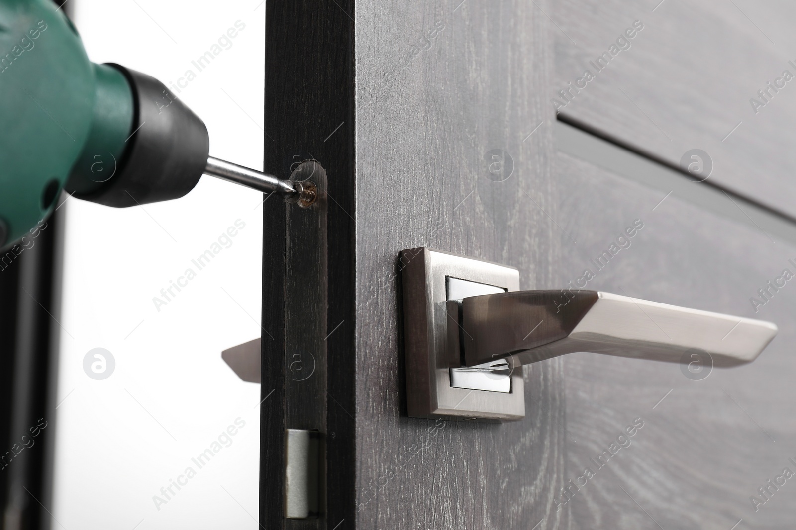 Photo of Repairing door handle with electric screwdriver indoors, closeup