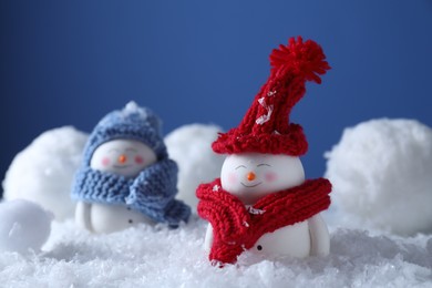 Photo of Cute decorative snowmen on snow against blue background