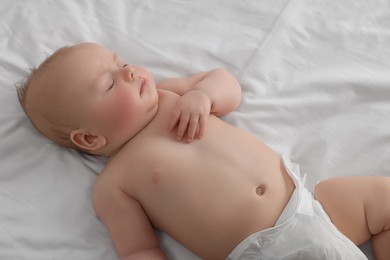 Photo of Cute newborn baby in diaper sleeping on bed at home
