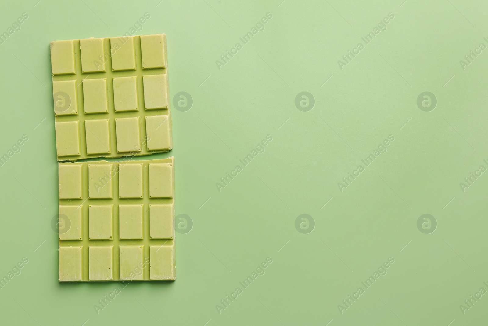 Photo of Tasty matcha chocolate bar on light green background, top view. Space for text