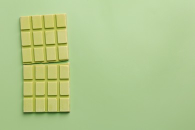 Tasty matcha chocolate bar on light green background, top view. Space for text