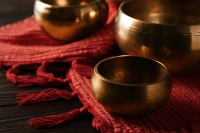 Photo of Tibetan singing bowls and red fabric on wooden table