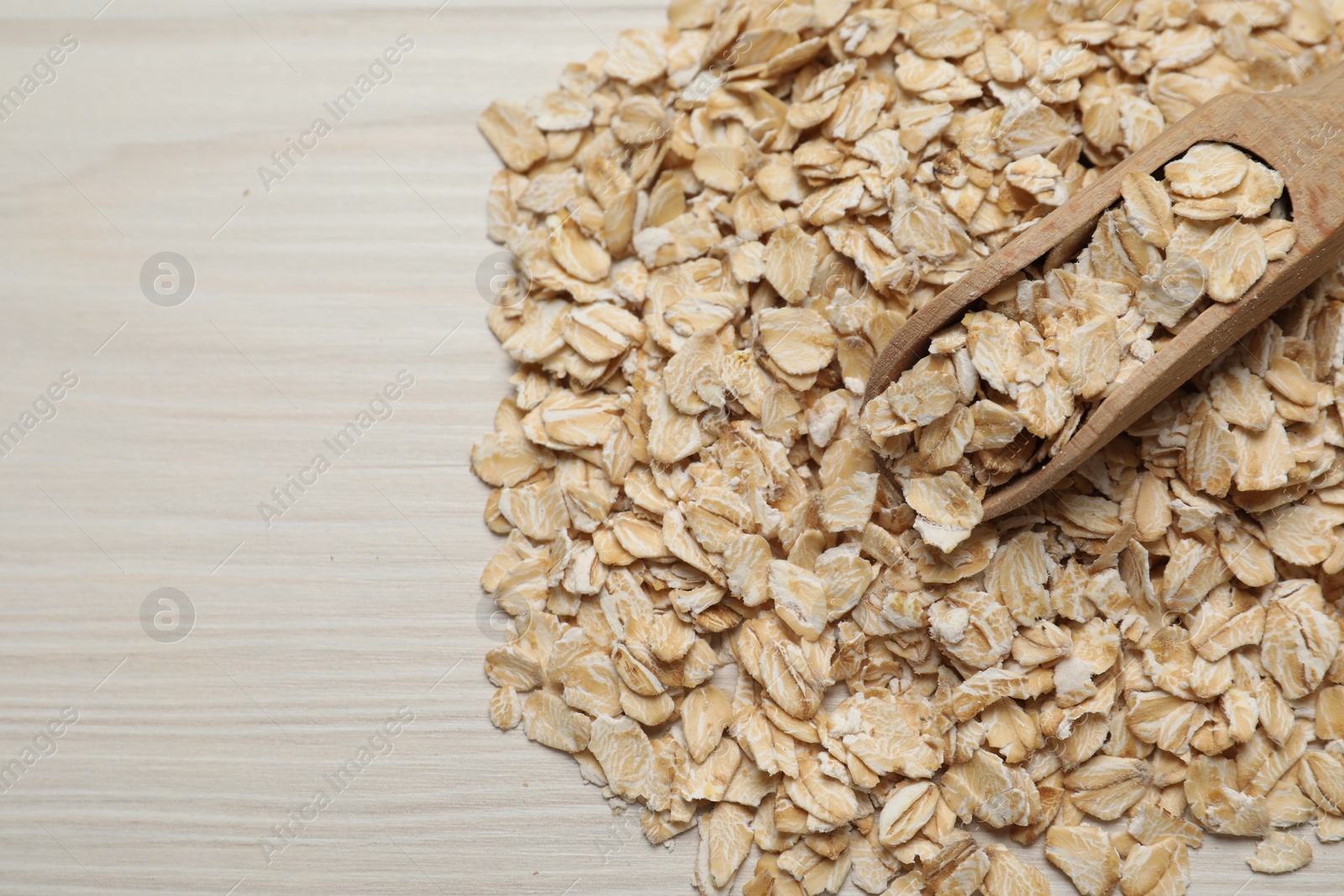 Photo of Scoop with oatmeal on white wooden table, top view. Space for text