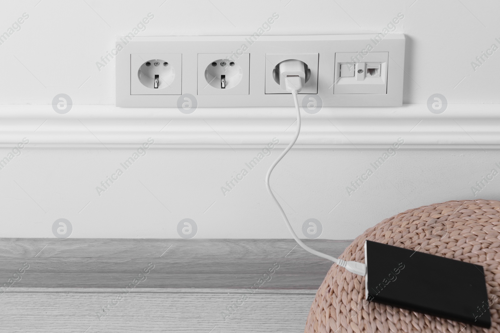Photo of Power bank plugged into electric socket on white wall