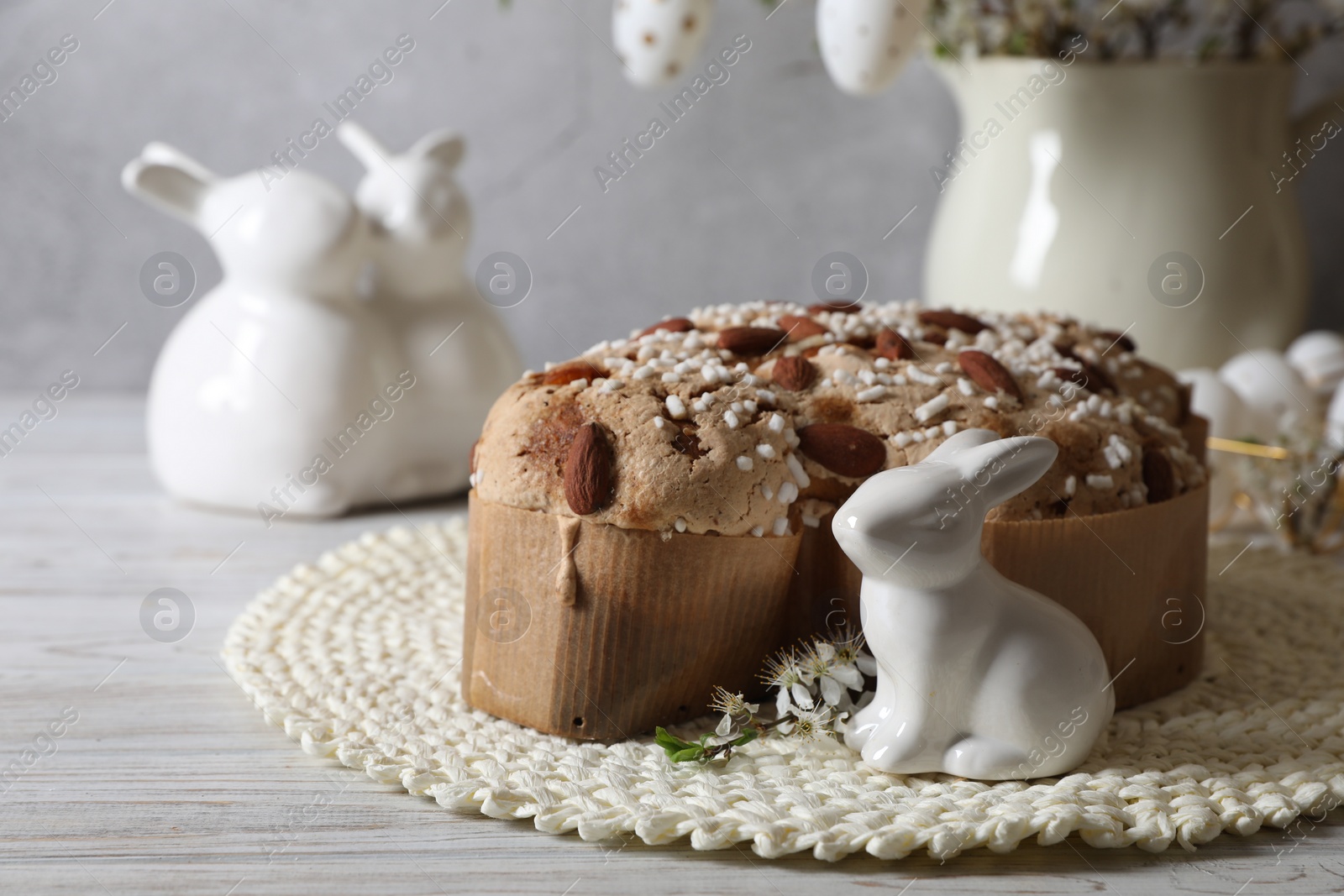 Photo of Delicious Italian Easter dove cake (Colomba di Pasqua) and festive decor on white wooden table. Space for text