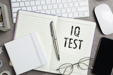 Image of Notebook with text IQ Test and stationery on grey table, flat lay