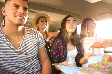 Happy friends with map in car on road trip