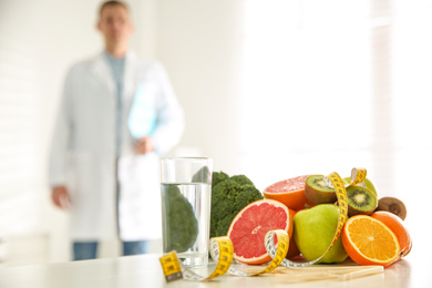 Photo of Healthy products, measuring tape and blurred nutritionist on background