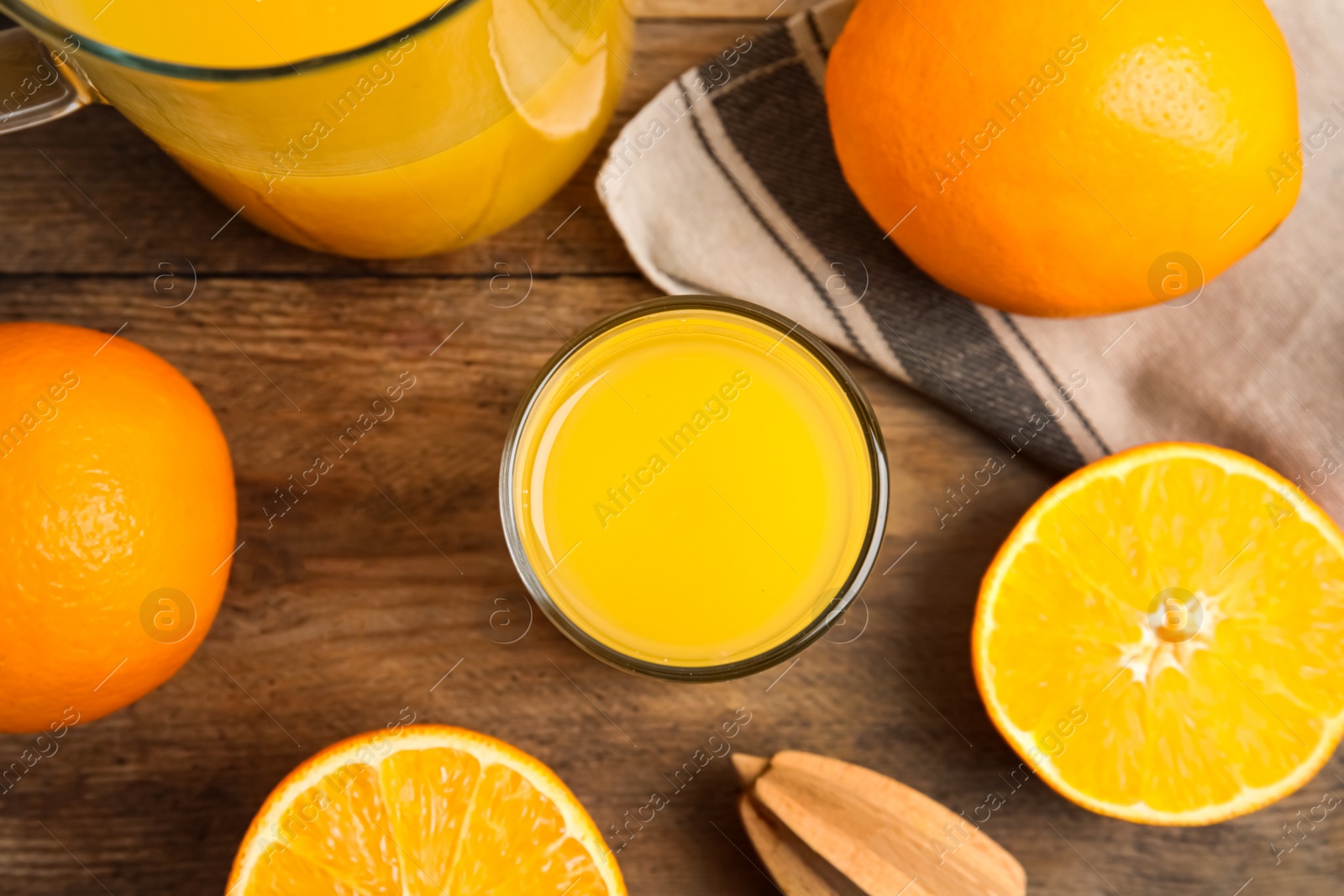 Photo of Fresh ripe oranges, reamer and juice on wooden table, flat lay