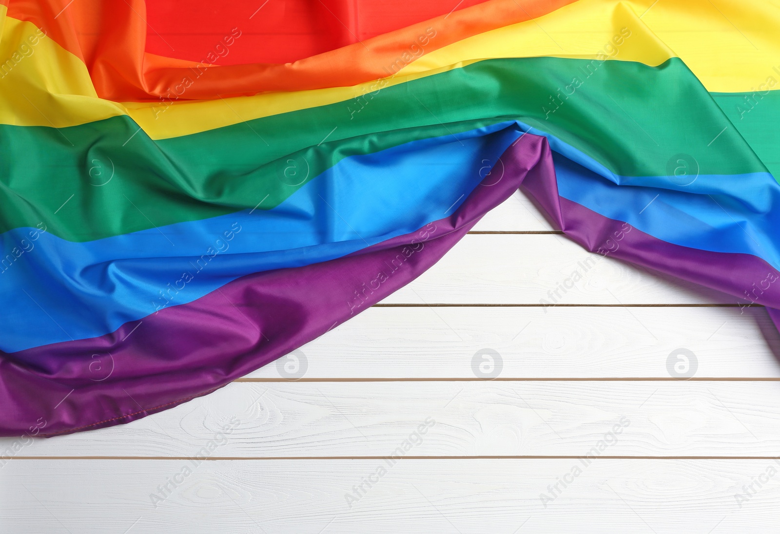 Photo of Bright rainbow gay flag on wooden background, top view with space for text. LGBT community