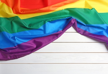 Photo of Bright rainbow gay flag on wooden background, top view with space for text. LGBT community