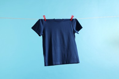One t-shirt drying on washing line against light blue background