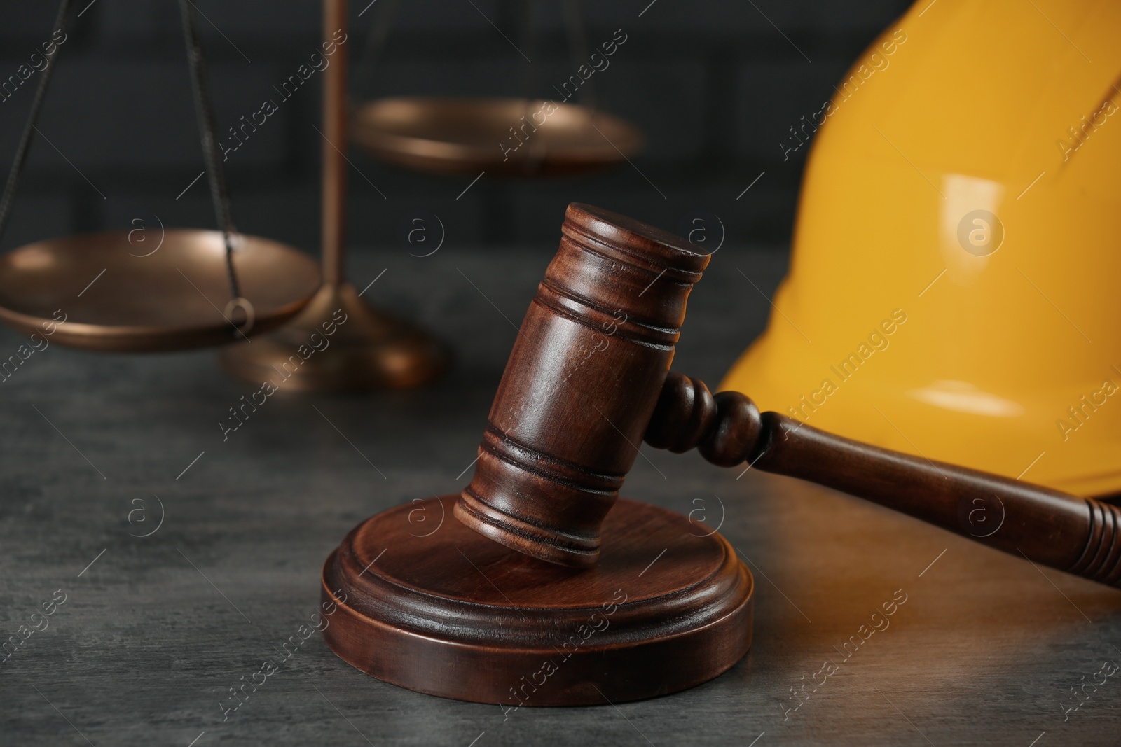 Photo of Labour, construction and land law concepts. Judge gavel, scales of justice with protective helmet on grey table, closeup