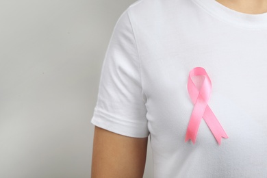 Woman with pink ribbon on grey background, space for text. Breast cancer awareness