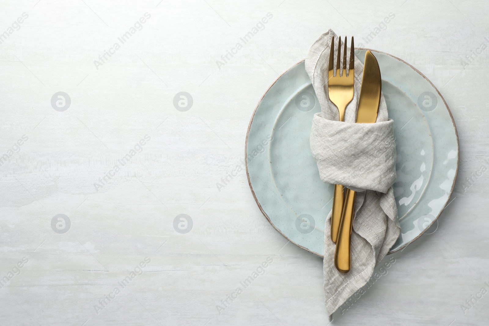 Photo of Stylish setting with cutlery, napkin and plates on white table, top view. Space for text