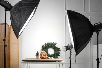 Photo of Professional equipment and Christmas composition with Pandoro cake on wooden table in studio. Food photography