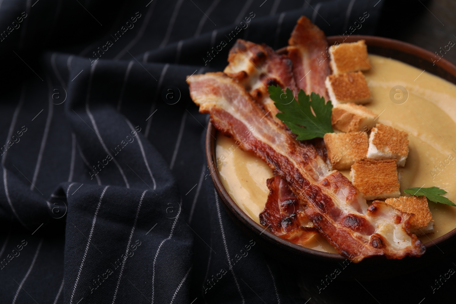 Photo of Delicious lentil soup with bacon and parsley in bowl on table, closeup