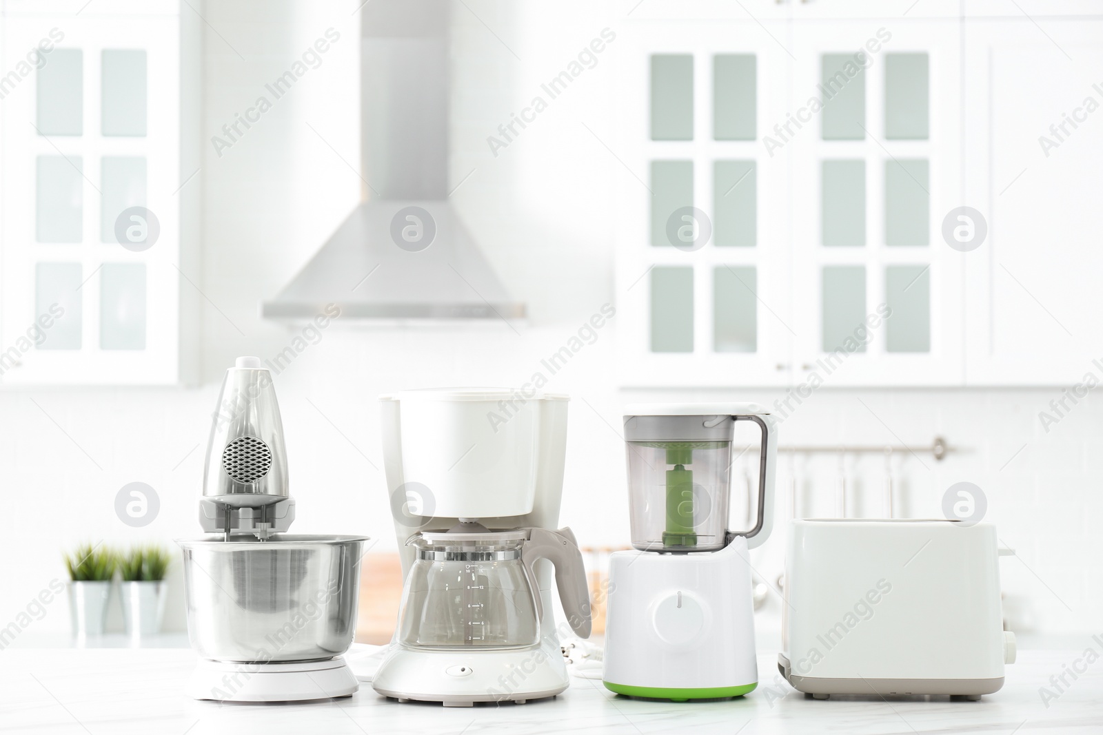 Photo of Modern toaster and other home appliances on white marble table in kitchen
