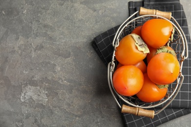 Photo of Delicious fresh persimmons on grey table, flat lay. Space for text