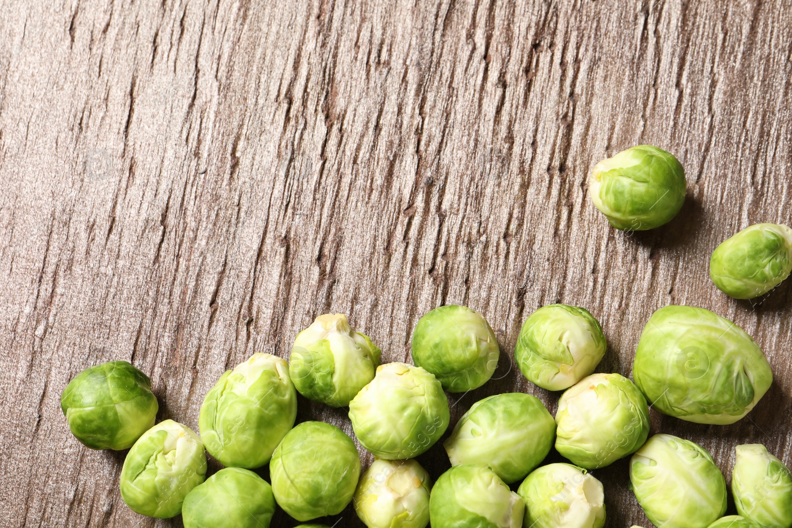 Photo of Fresh Brussels sprouts on wooden table, top view. Space for text