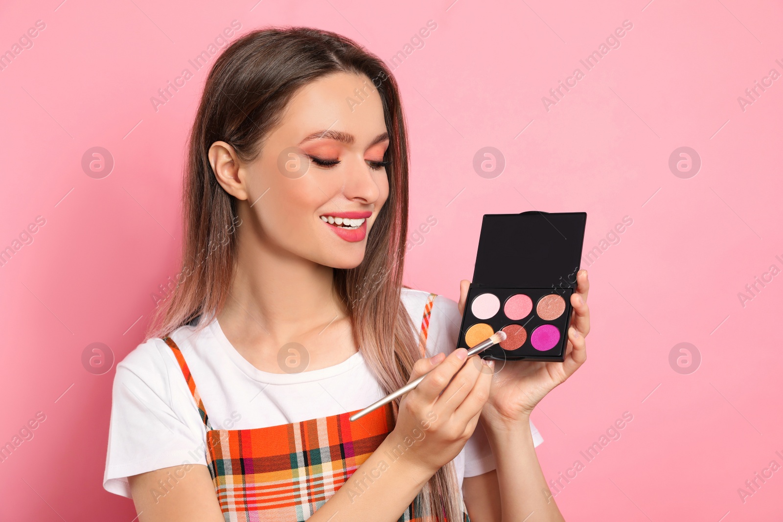 Photo of Beauty blogger with brush and eyeshadow palette on pink background
