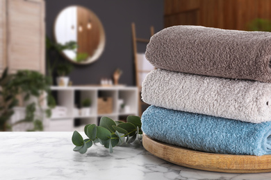 Fresh towels and eucalyptus branches on marble table in bathroom. Space for text