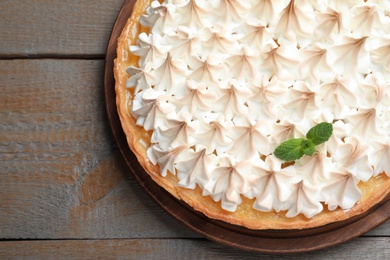 Delicious lemon meringue pie decorated with mint on wooden table, top view. Space for text