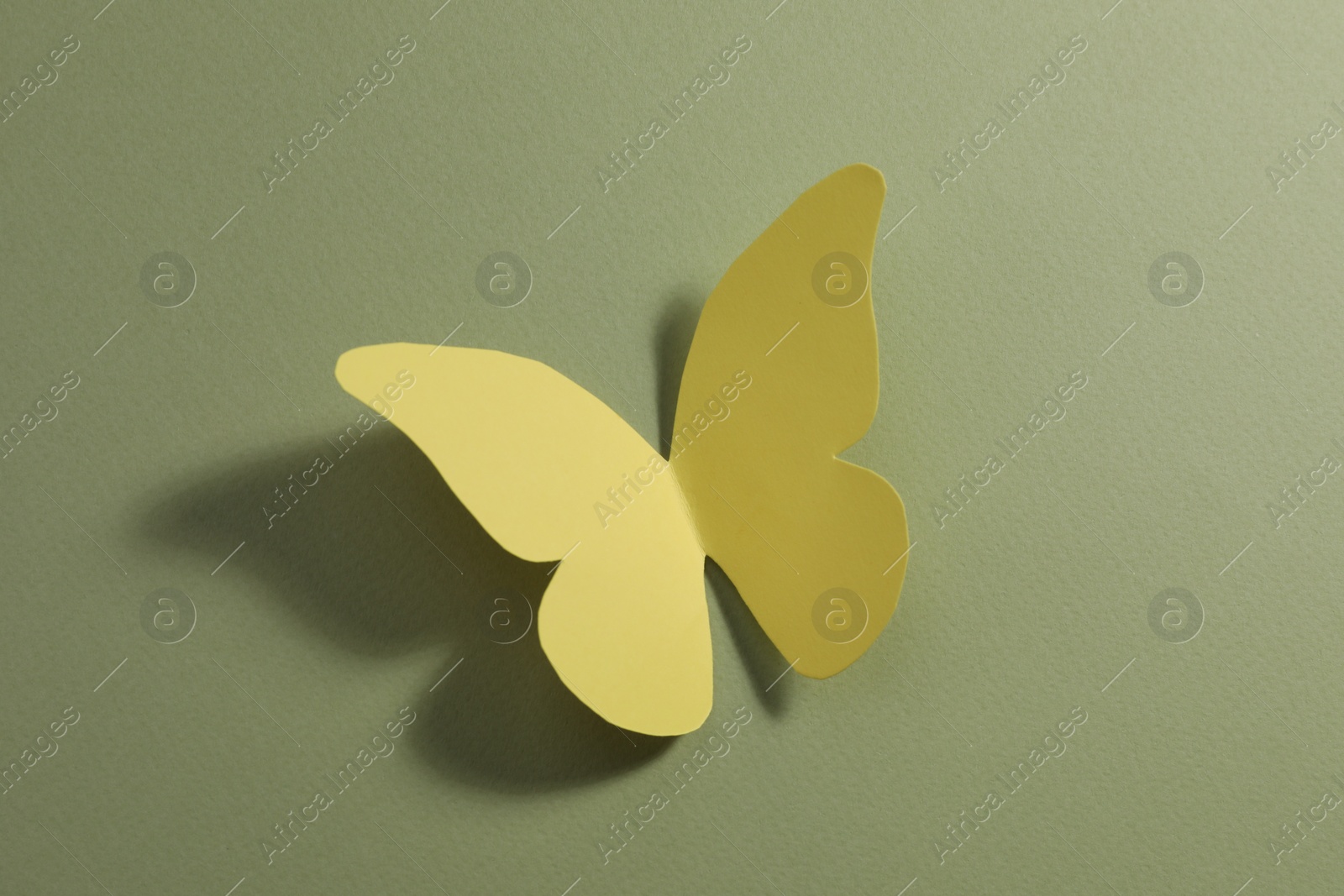 Photo of Yellow paper butterfly on pale green background, top view
