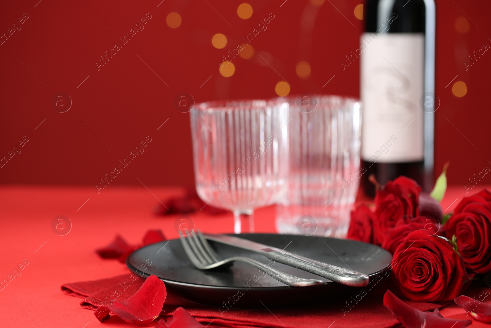 Photo of Place setting with roses for romantic dinner on red table, closeup. Space for text