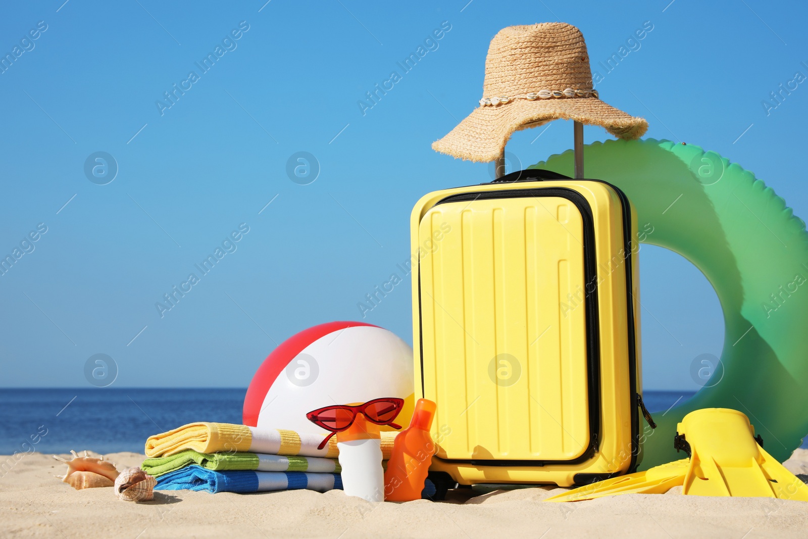 Photo of Suitcase and stylish beach accessories on seaside