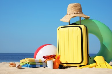 Suitcase and stylish beach accessories on seaside