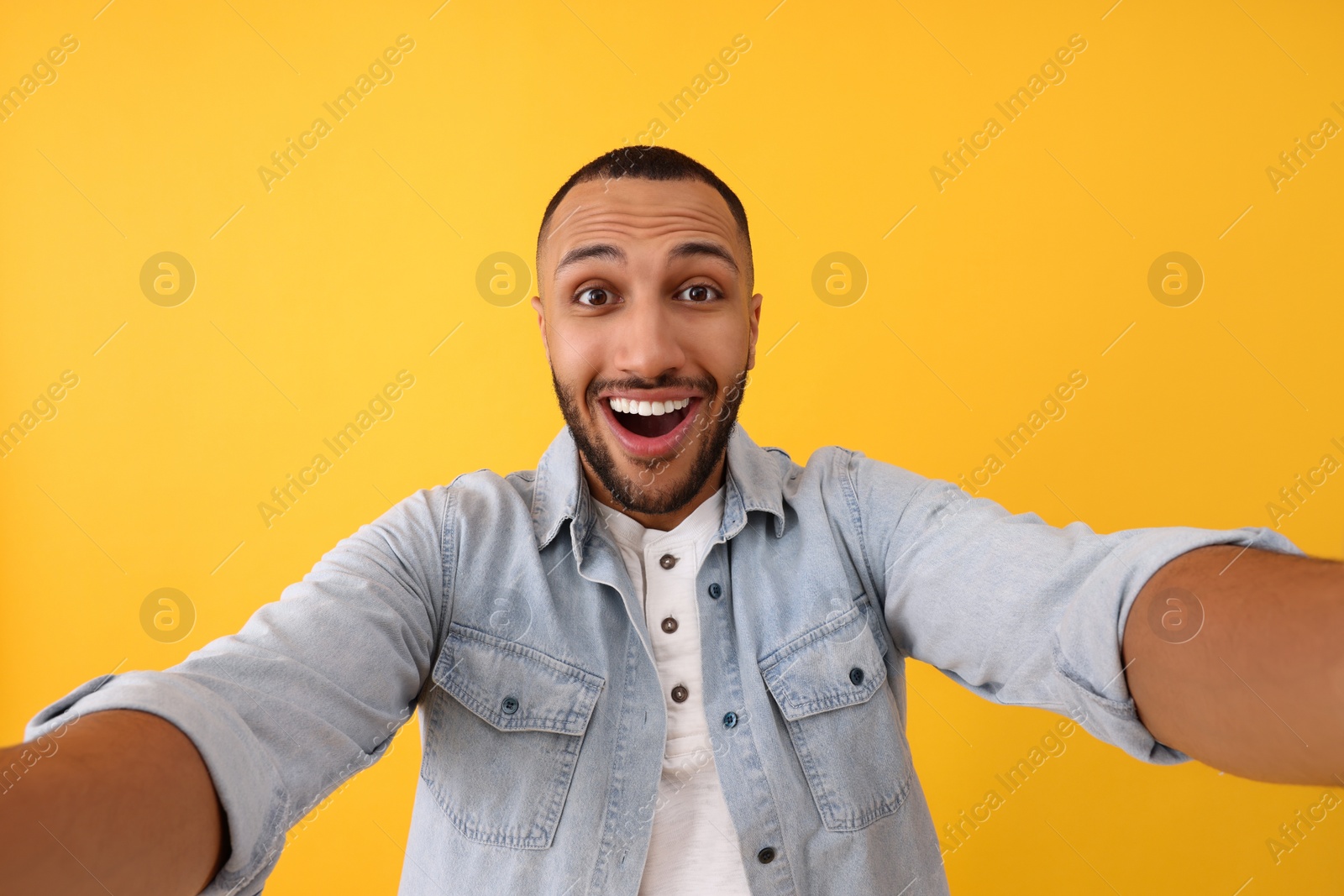 Photo of Smiling young man taking selfie on yellow background