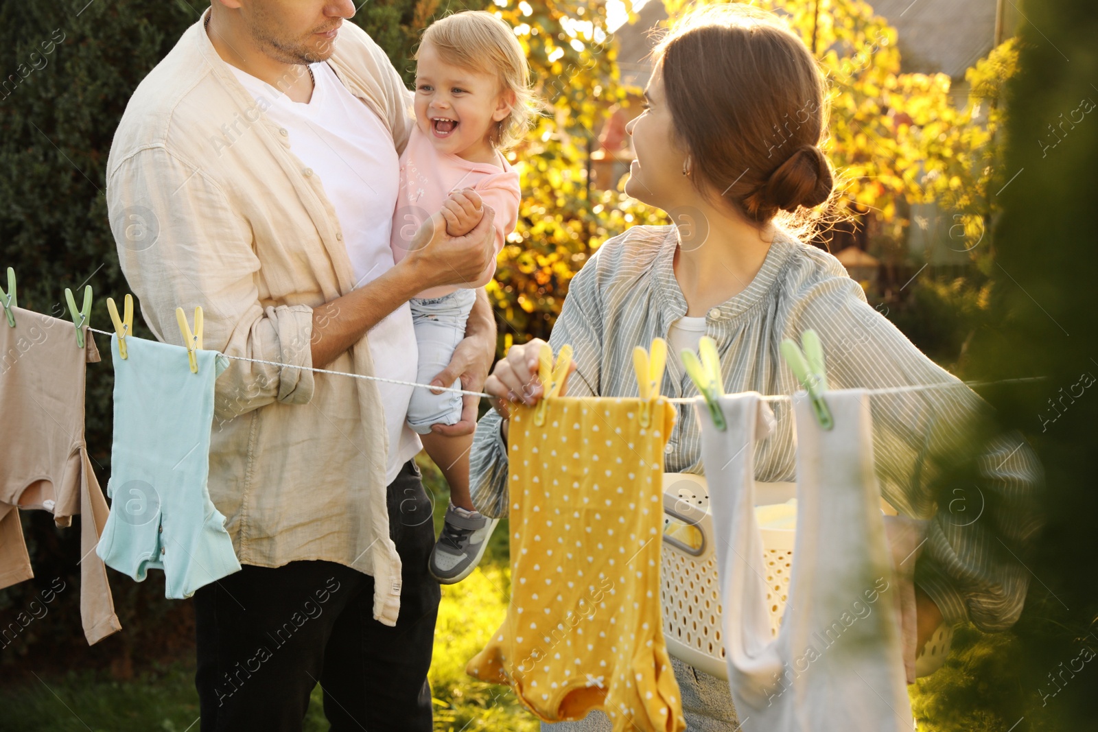 Photo of Happy family near washing line with drying clothes in backyard