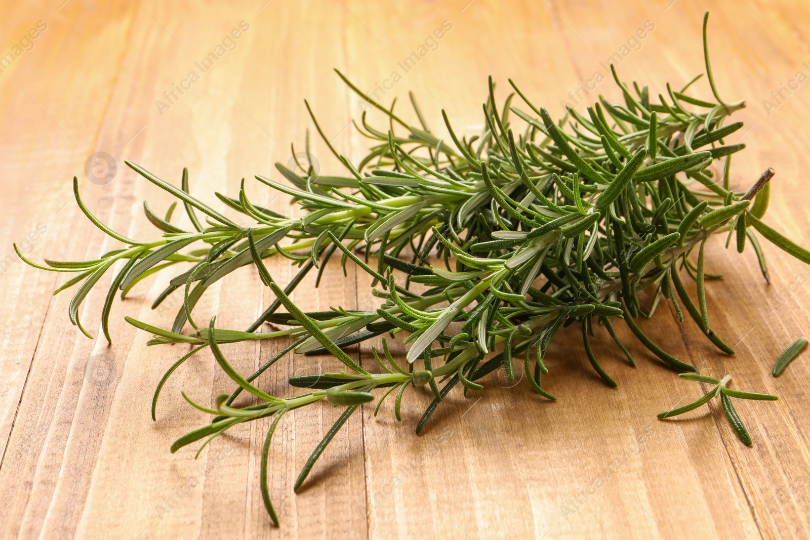 Photo of Sprigs of fresh rosemary on wooden table, closeup