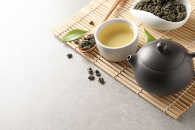 Teapot and cup of Tie Guan Yin oolong on grey table. Space for text