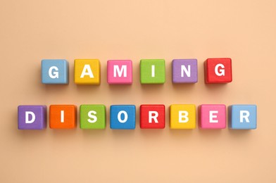 Photo of Phrase Gaming Disorder made of colorful cubes on beige background, flat lay. Addictive behavior
