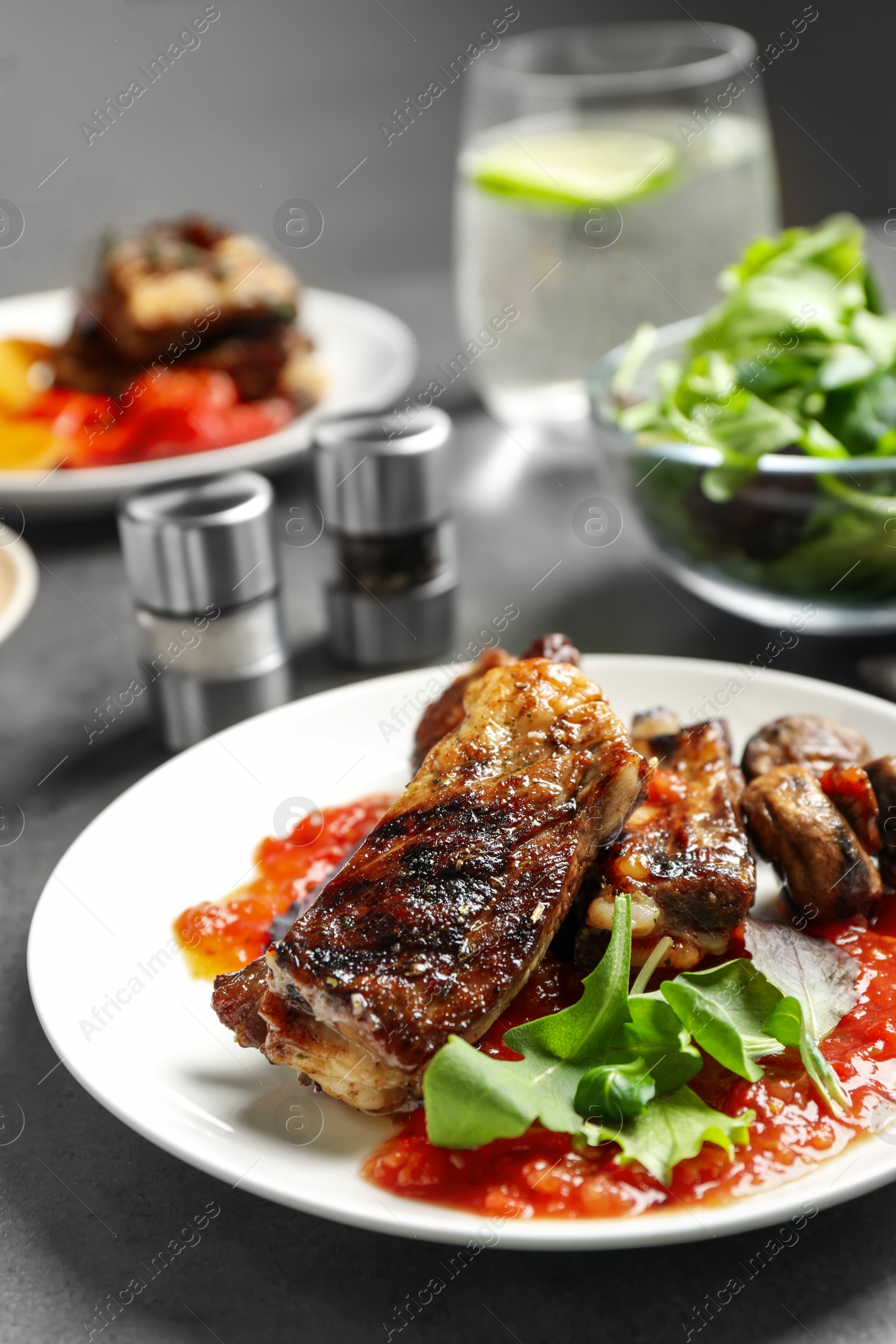 Photo of Delicious grilled ribs served on grey table