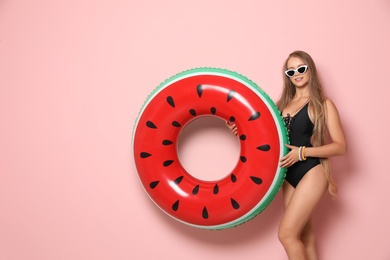 Photo of Beautiful young woman in bikini with inflatable ring against color background. Space for text