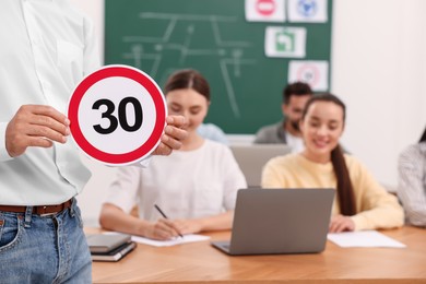 Teacher showing Speed Limit road sign during lesson in driving school, closeup. Space for text