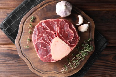 Photo of Piece of raw beef meat, thyme and garlic on wooden table, top view