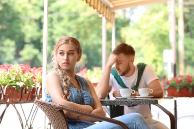 Young couple arguing while sitting in cafe, outdoors. Problems in relationship