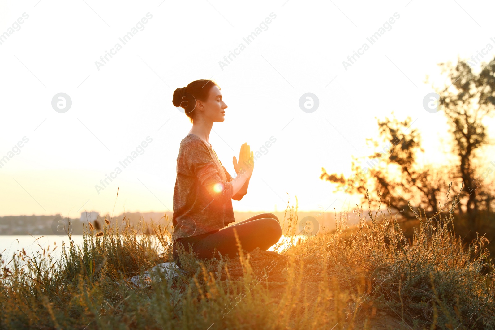 Photo of Young woman practicing yoga outdoors on sunset. Zen meditation