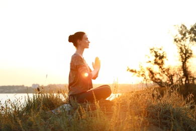 Photo of Young woman practicing yoga outdoors on sunset. Zen meditation