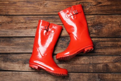 Photo of Pair of red rubber boots on wooden background, top view