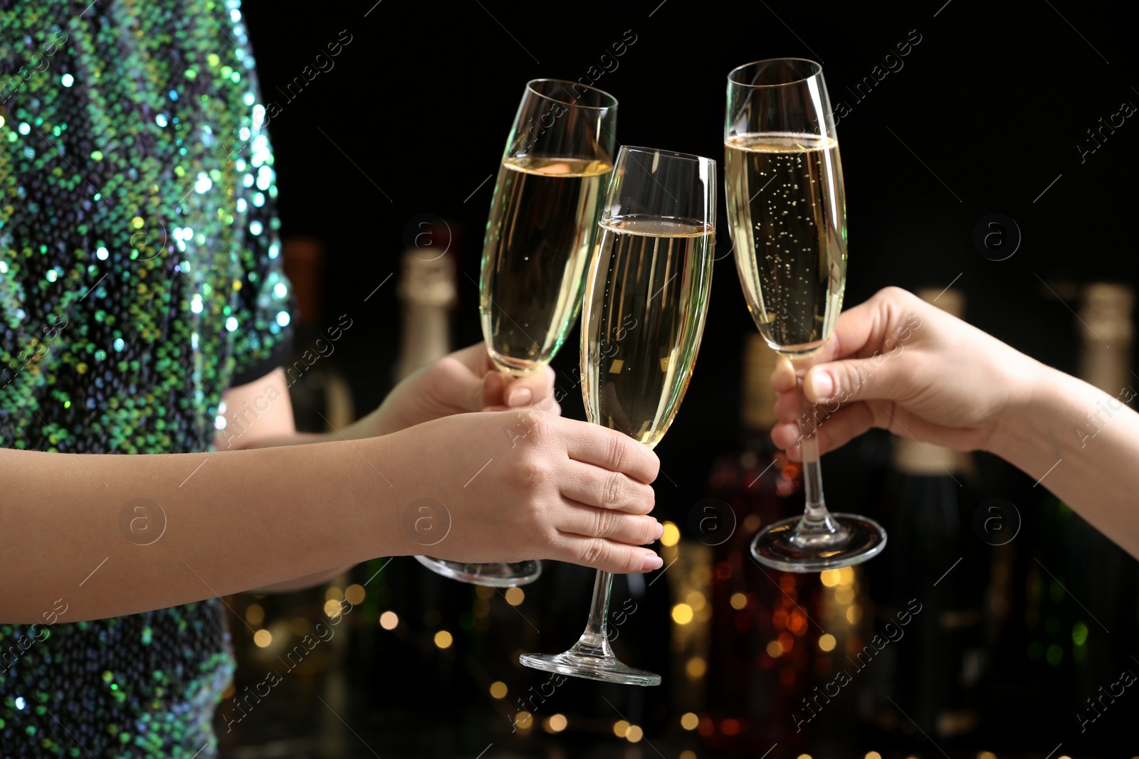 Photo of People clinking glasses of champagne on blurred background, closeup