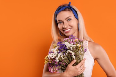 Photo of Happy hippie woman with bouquet of flowers on orange background. Space for text