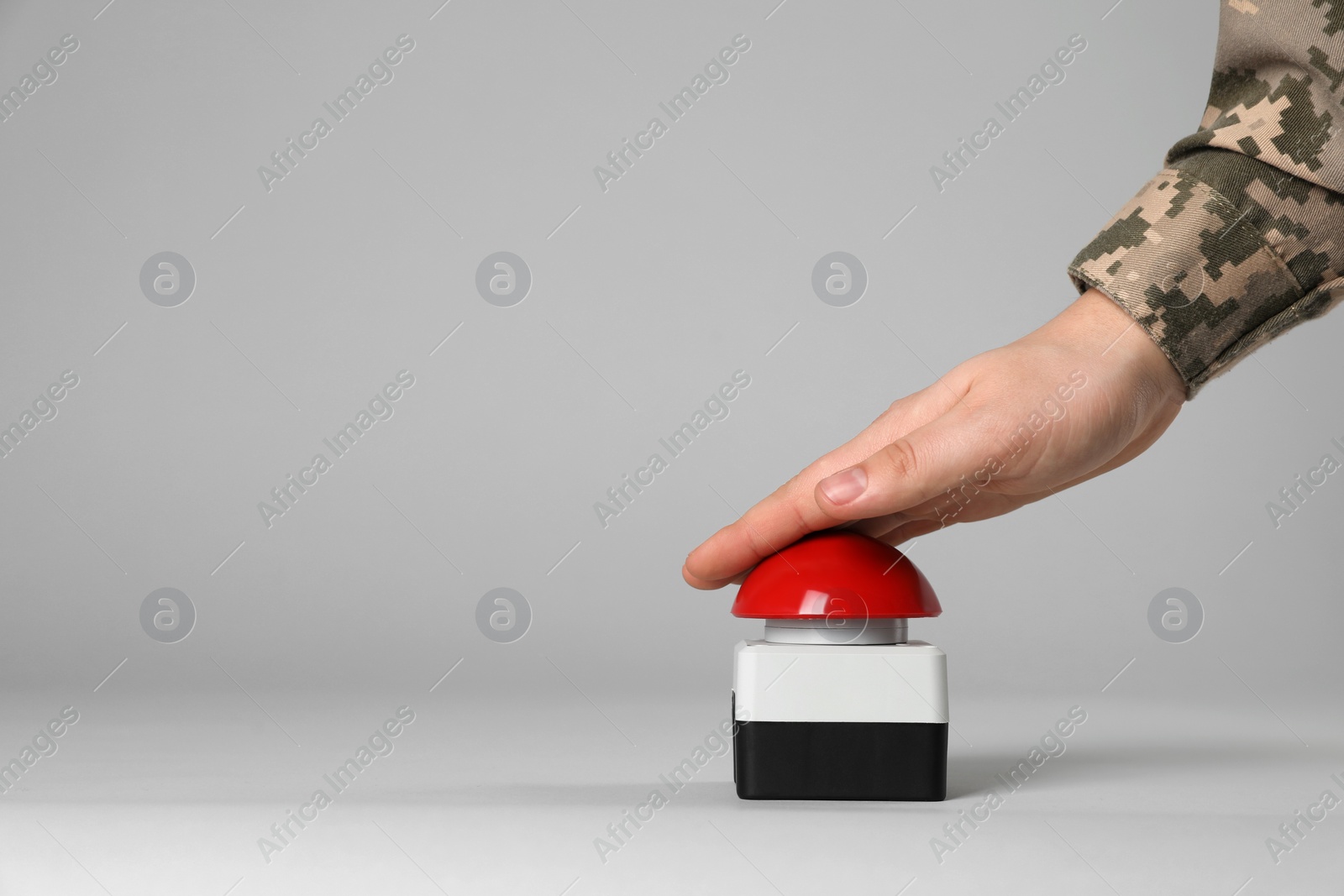 Photo of Serviceman pressing red button of nuclear weapon on light gray background, closeup with space for text. War concept