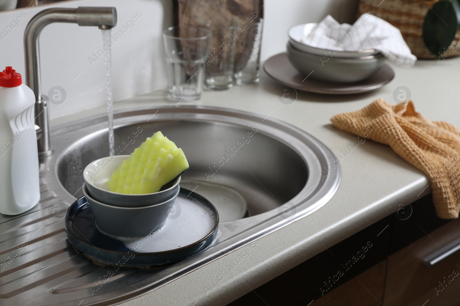 Photo of Bowls and sponge on kitchen sink. Washing dishes