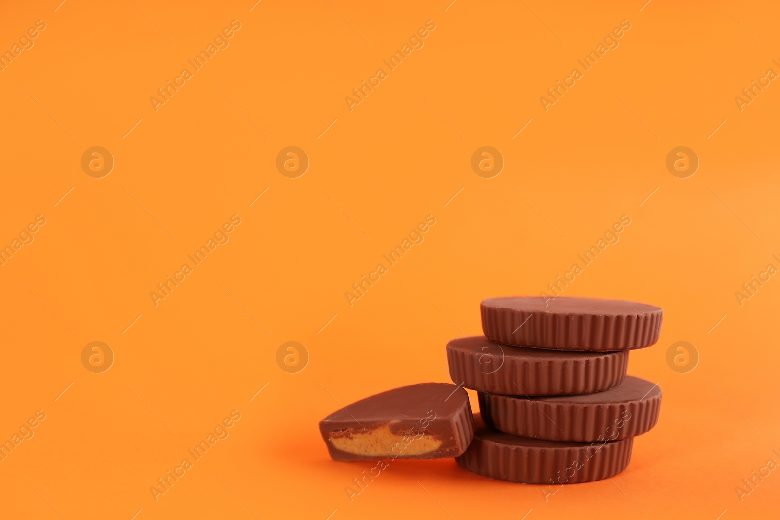 Photo of Sweet peanut butter cups on orange background. Space for text